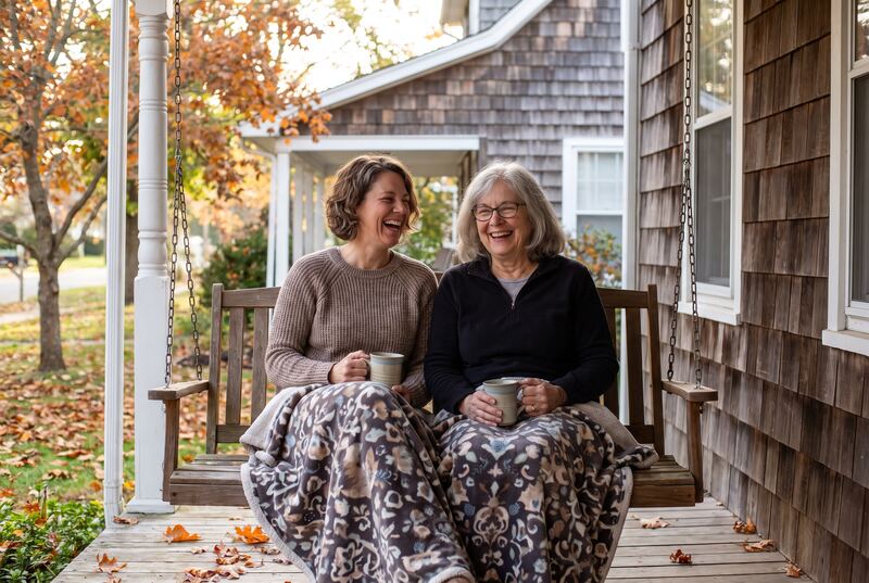 A mother and her grown daughter sharing a laugh on a porch swing (an illustration)